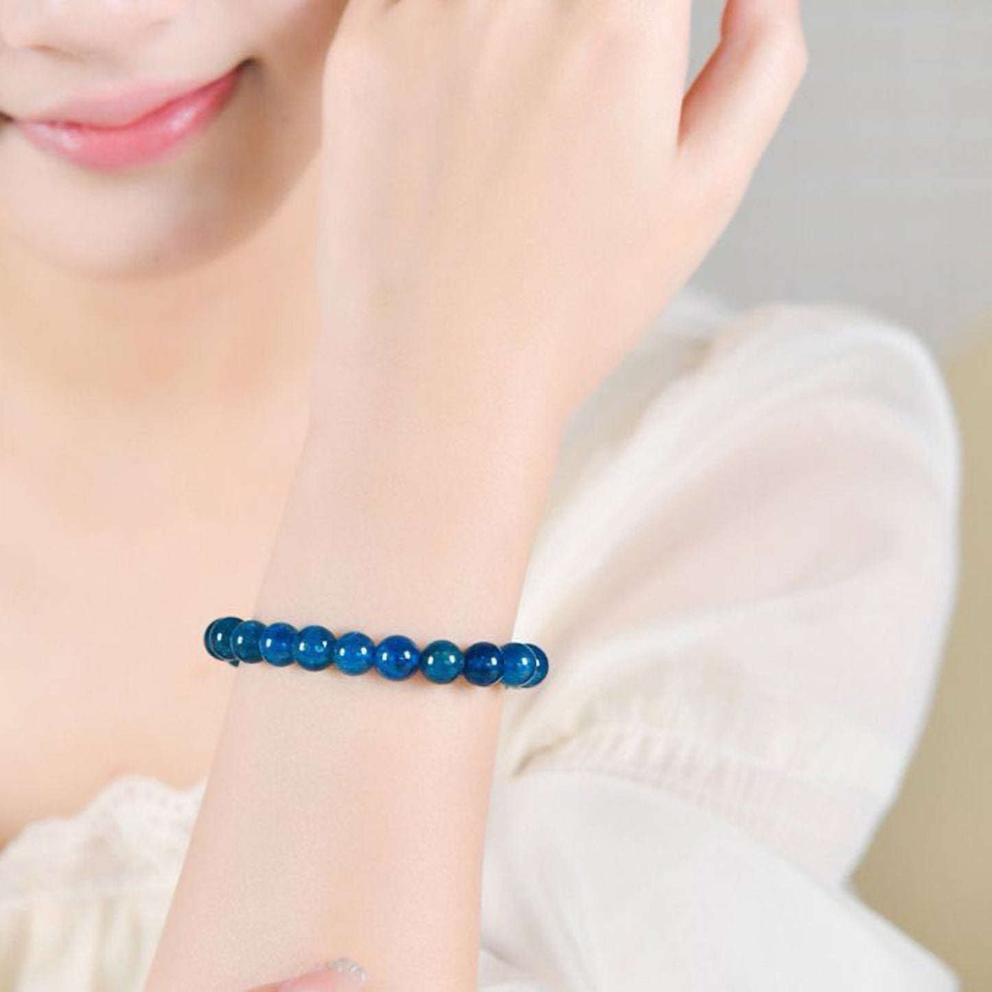 Close-up of elegant natural blue apatite crystal bracelet with 8mm beads on a woman's wrist